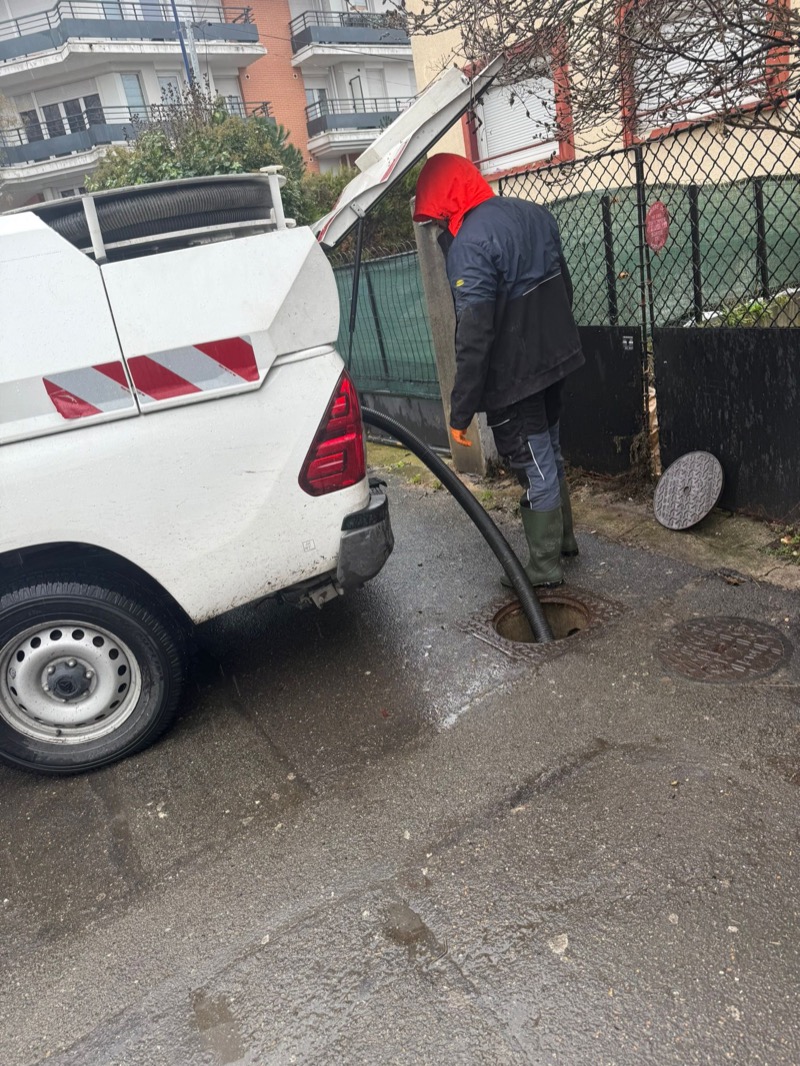 Technicien avec camion et tuyau haute pression en rue