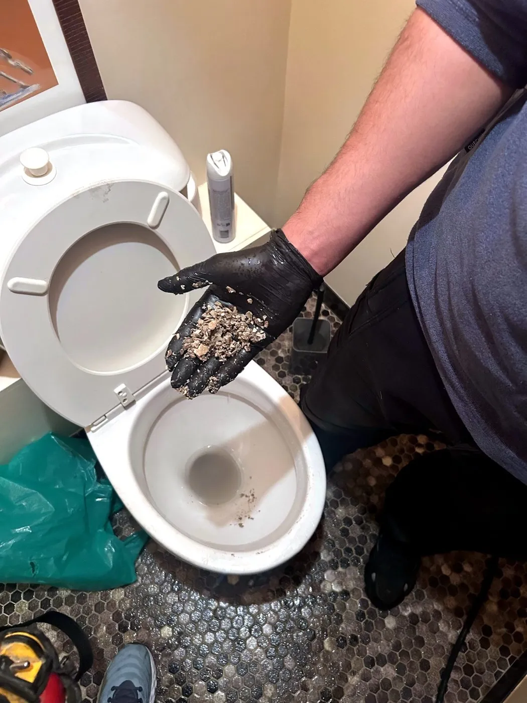 Technicien montrant les déchets retirés d'un WC bouché