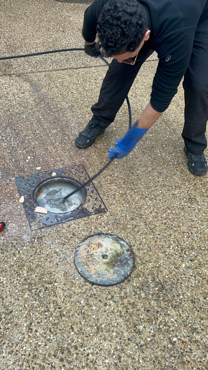 Technicien débouchage regard au sol extérieur