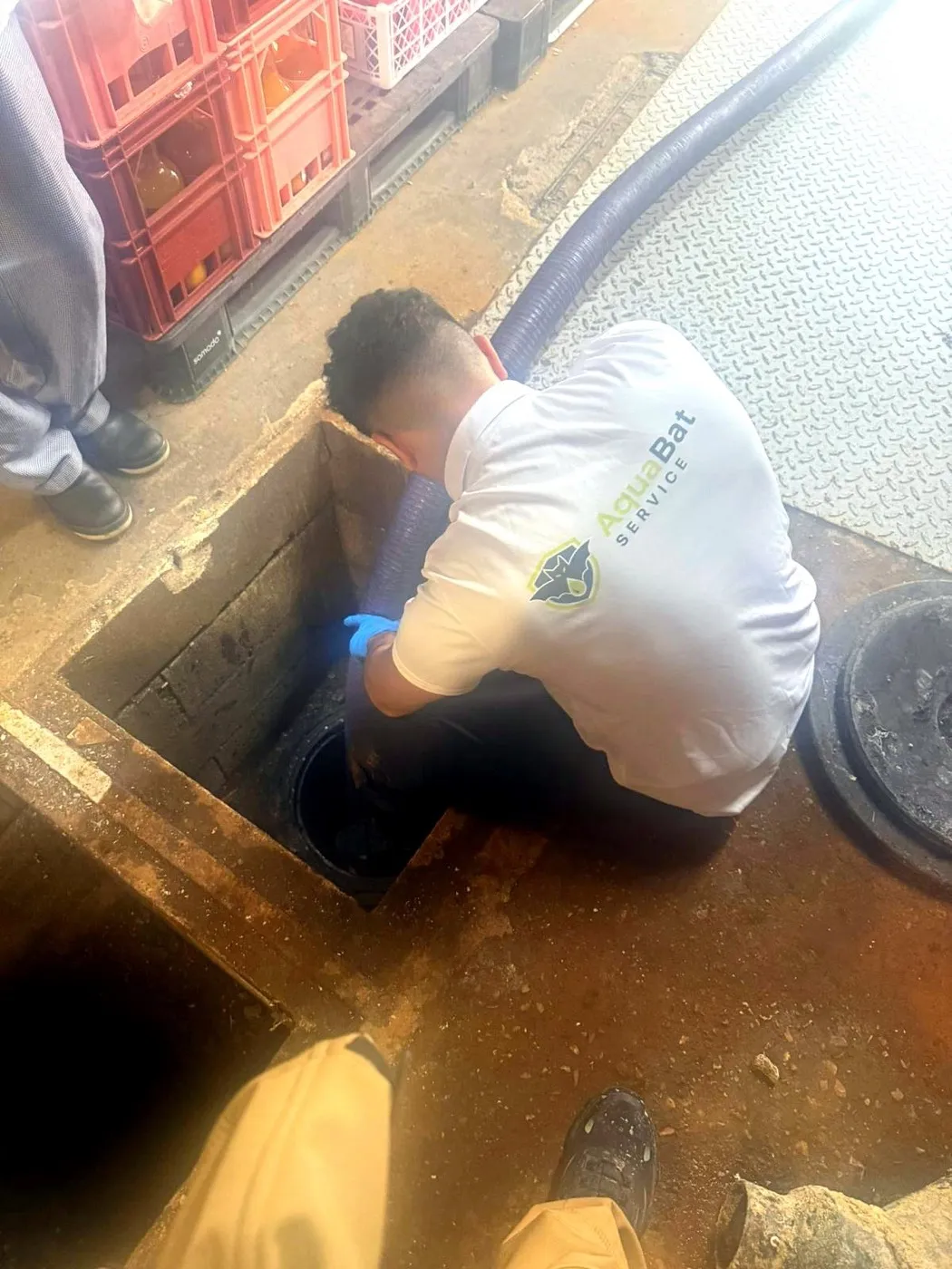 Technicien AquaBat en chemise floquée intervenant sur un regard