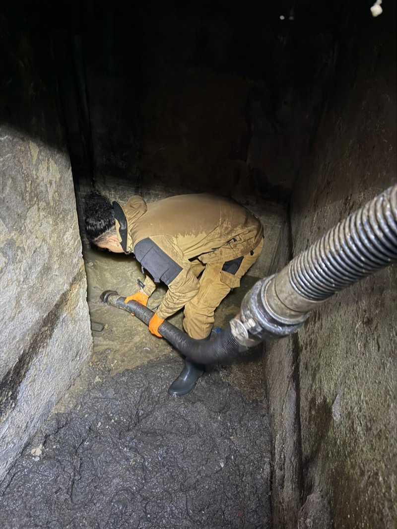 Technicien dans regard souterrain avec tuyau